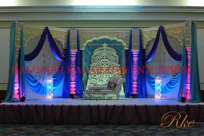 wedding reception stage with Rajasthani carved design cutwork pillar off-white finishing with pearl and gold shade looks shinning in lighting of evening time of wedding venue palace in banquet hall 